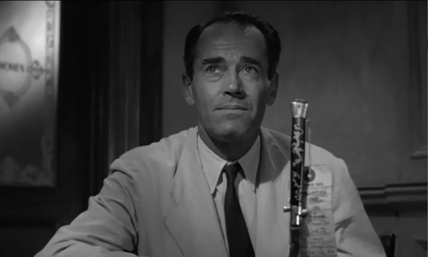 Calm white man wearing a neat white suit and tie, with a switchblade in front of him